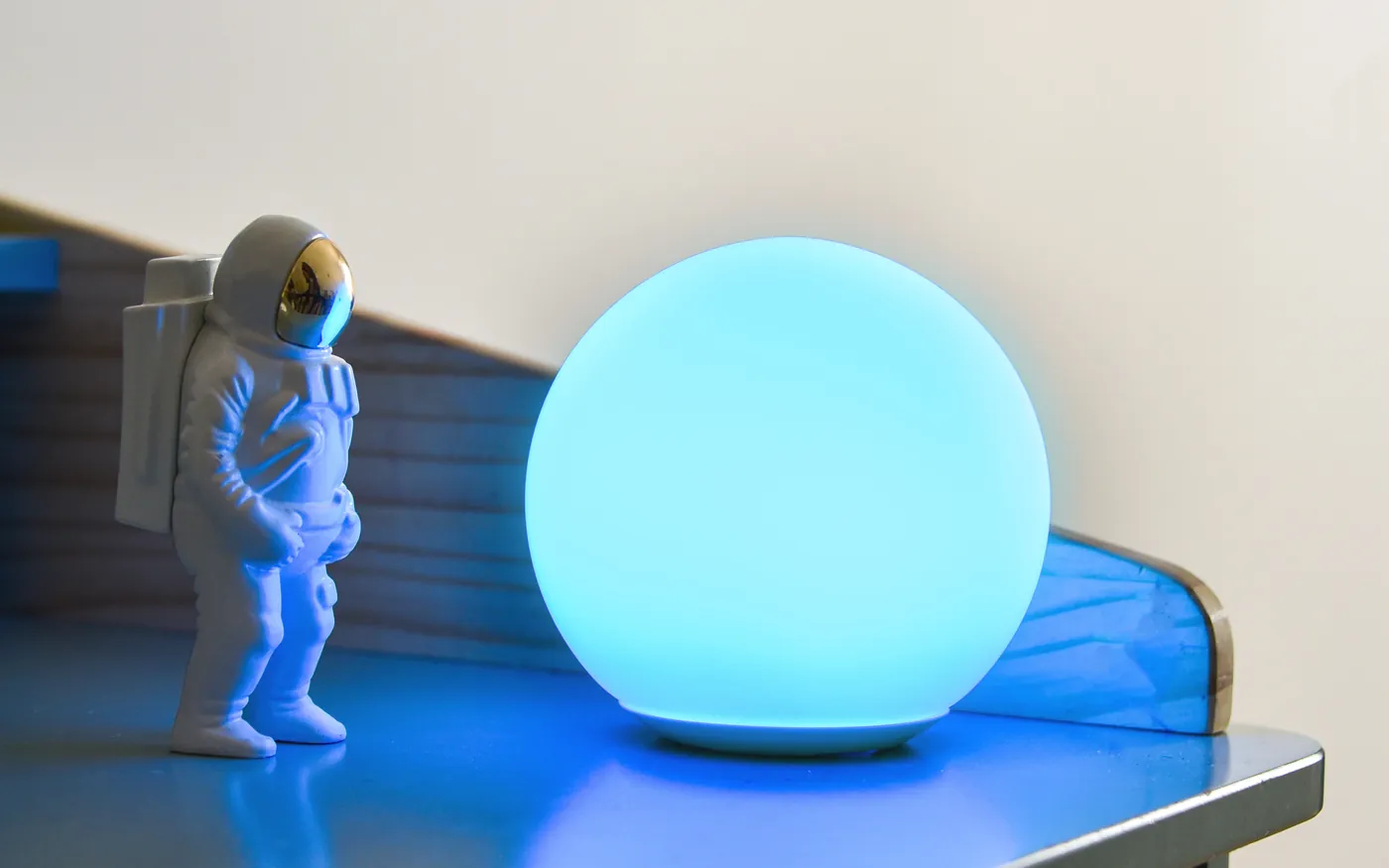 A blue SensoLight glowing on a white desk beside an astronaut figurine